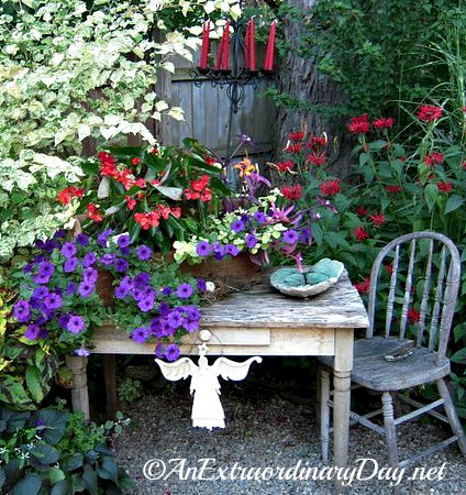 A rustic box placed on an old table filled with flowers for a sweet container garden