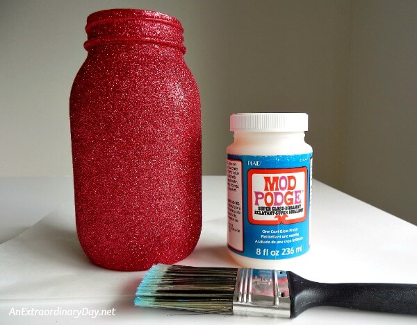 Mason Jar covered in fine glitter for some 4th of July sparkle prior to its final coat of Mod Podge - AnExtraordinaryDay.net