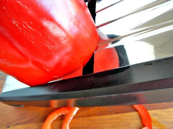 Slicing a red pepper with a mandoline vegetable slicer at AnExtraordinaryDay.net