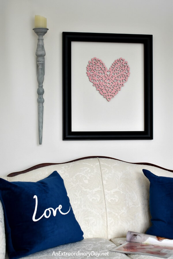 Simple pink heart DIY Valentine wall art hangs over a French country couch in this small space living room - AnExtraordinaryDay.net