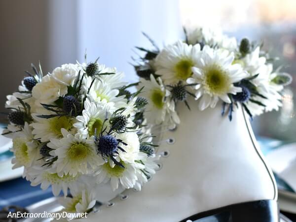 White Mums and Blue Sea Holly Fill the Tops of Ladies Figure Skates for a Winter Table Centerpiece - AnExtraordinaryDay.net