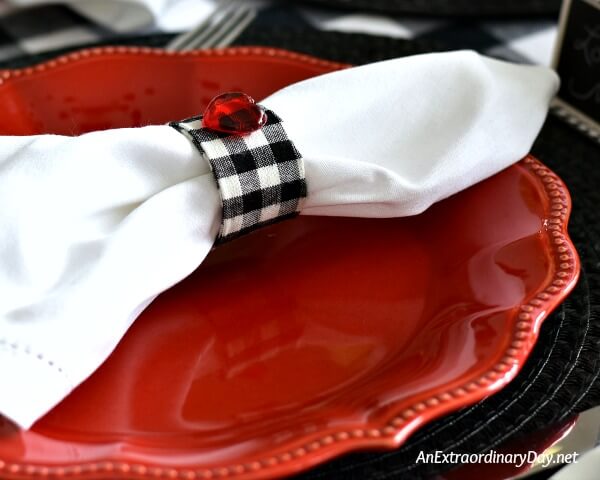 White napkin with black and white checked napkin ring on red plate for Valentine's Day - AnExtraordinaryDay.net