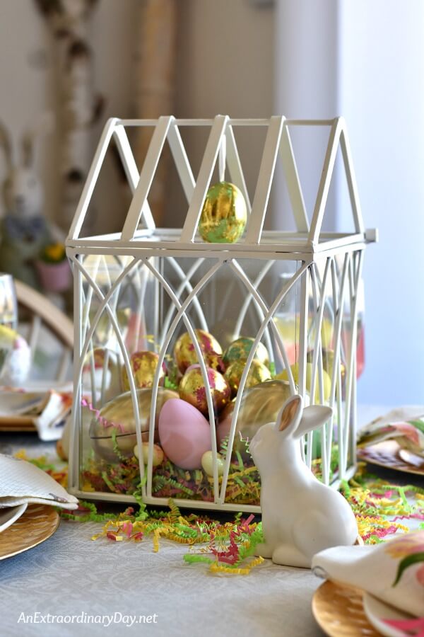 aux white greenhouse filled with eggs and white ceramic bunnies make an Easter centerpiece - AnExtraordinaryDay.net