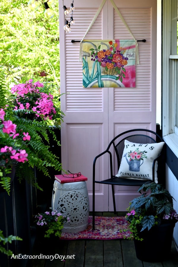 Small outdoor balcony and tiny sitting area decorated in pink for summer with a French Quarter garden theme.
