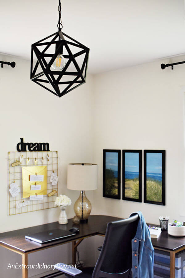 A view of a home office from the geometric black metal ceiling light to the wall decor and lamp on the table. It's all about personalizing the work from home office space.